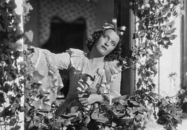 Scena del film "La donna perduta" - Regia Domenico Gambino, 1940 - Mezza figura di Elli Parvo affacciata a un davanzale incorniciato dall'edera. L'attrice ha una rosa in mano.