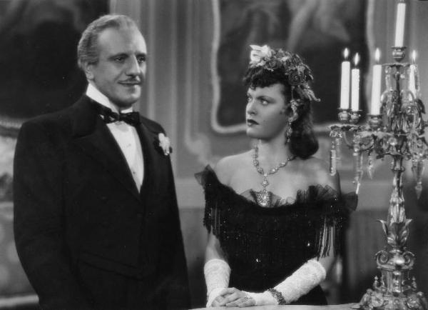 Scena del film "La donna perduta" - Regia Domenico Gambino, 1940 - Mezza figura di Alberto Capozzi ed Elli Parvo. L'attore guarda davanti a sé, mentre, l'attrice, guarda verso di lui.