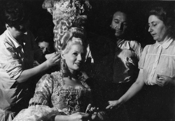 Sul set del film "Don Pasquale" - Regia Camillo Mastrocinque, 1940 - Un parrucchiere ritocca la parrucca di Laura Solari.