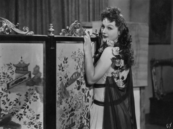 Scena del film "Don Pasquale" - Regia Camillo Mastrocinque, 1940 - Mezza figura, di tre quarti di Greta Gonda. L'attrice è appoggiata a un separè per interni con entrambe le mani sulla sua sommità.