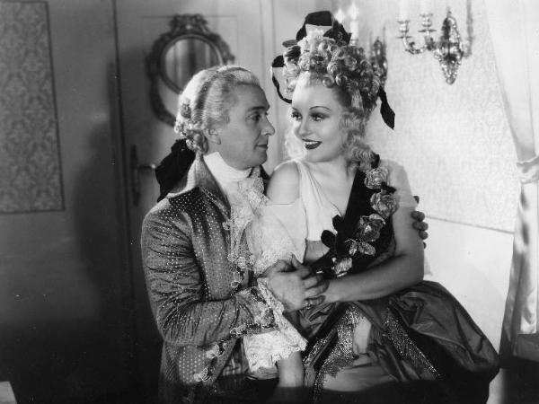 Scena del film "Don Pasquale" - Regia Camillo Mastrocinque, 1940 - Mezza figura di profilo di Maurizio D'Ancora e di Laura Solari che gli siede in braccio.