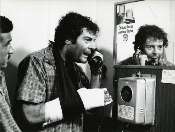 Scena del film "Dramma della gelosia (tutti i particolari in cronaca)" - Regia Ettore Scola, 1970 - Marcello Mastroianni mentre parla a un telefono pubblico. Al suo fianco un attore non identificato.