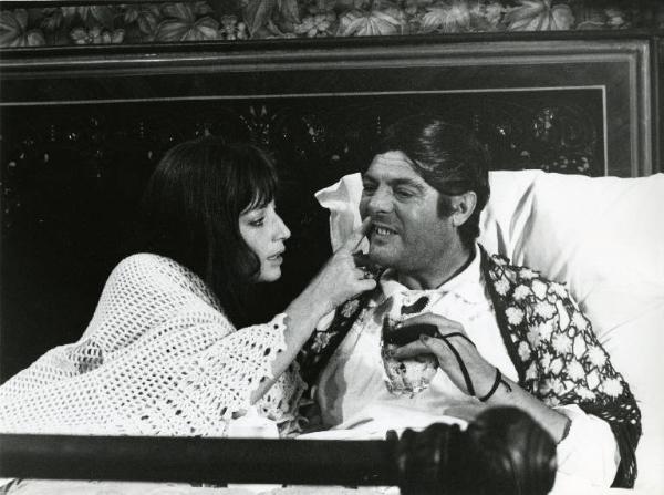 Scena del film "Dramma della gelosia (tutti i particolari in cronaca)" - Regia Ettore Scola, 1970 - Monica Vitti e Marcello Mastroianni seduti a letto. L'attrice è intenta a osservare i denti dell'attore.