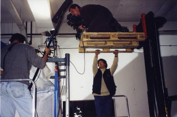 Sul set del film "Due dollari al chilo" - Regia Paolo Lipari, 2000 - Un operatore su un muletto riprende dall'alto una scena guardando nel mirino della macchina da presa.