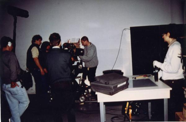 Sul set del film "Due dollari al chilo" - Regia Paolo Lipari, 2000 - A sinistra la troupe prepara la macchina da presa; a destra un'operaia si accinge a processare una bobina di pellicola 35 mm.