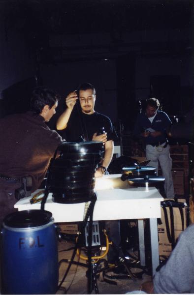 Sul set del film "Due dollari al chilo" - Regia Paolo Lipari, 2000 - Un operaio al tavolo mentre processa una pellicola 35 mm. Attorno a lui, la troupe si dispone a riprendere la scena.