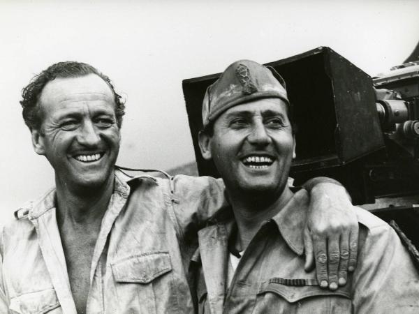 Sul set del film "I due nemici" - Regia Guy Hamilton, 1961- A sinistra, David Niven poggia il braccio sulla spalla di Alberto Sordi, a destra.