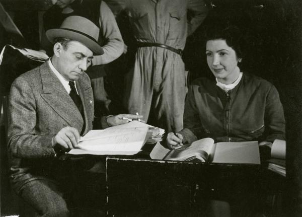 Sul set del film "Due occhi per non vedere" - Regia Gennaro Righelli, 1939 - Il regista Gennaro Righelli, a sinistra, e un'operatrice, a destra, consultano dei documenti.