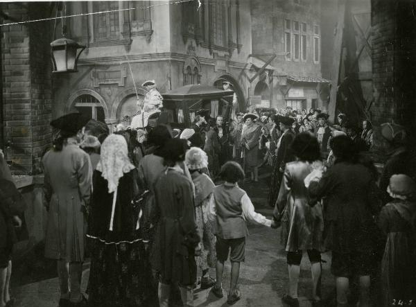 Scena del film "Le due orfanelle" - Regia Carmine Gallone, 1942 - Alcuni attori non identificati discutono davanti a una carrozza. Attorno a loro, attori e attrici non identificati osservano la scena.