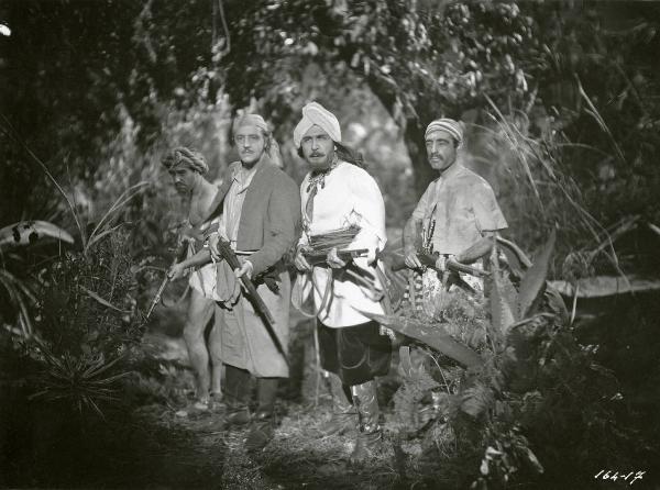 Scena del film "Le due tigri" - Regia Giorgio Candido Simonelli, 1941- Al centro sono presenti Sandro Ruffini, a sinistra, e Luigi Pavese, a destra, mentre brandiscono un fucile. Alle loro spalle, due attori non identificati.