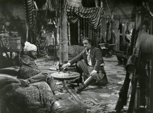 Scena del film "Le due tigri" - Regia Giorgio Candido Simonelli, 1941- Sulla sinistra, Luigi Pavese semidisteso mentre osserva Sandro Ruffini, a destra, seduto con una sigaretta in bocca, intento a giocare a dadi.