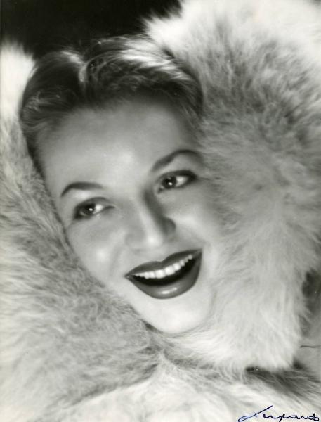 Scena del film "È caduta una donna" - Regia Alfredo Guarini, 1941 - Primo piano di Maria Dominiani sorridente e avvolta in una pelliccia.