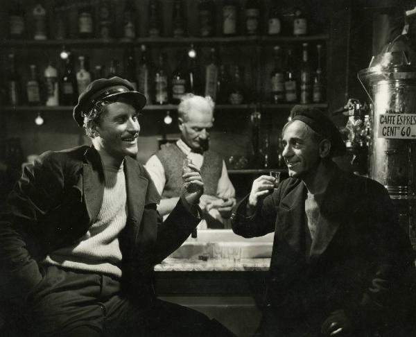 Scena del film "È sbarcato un marinaio" - Regia Piero Ballerini, 1940 - Amedeo Nazzari, a sinistra, e Polidor, a destra, tengono un bicchiere in mano. Alle loro spalle un attore non identificato asciuga un bicchiere.