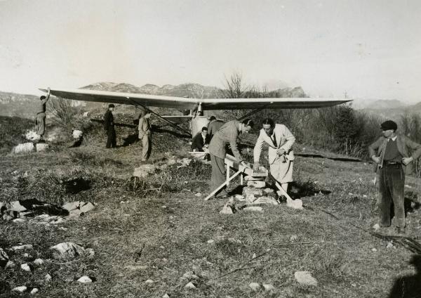 Sul set del film "L'ebbrezza del cielo" - Regia Giorgio Ferroni, 1940 - Sandro Pallavicini, a destra, e Giorgio Ferroni, a sinistra, verificano le attrezzature per il lancio dell'aliante. Alle loro spalle operatori non identificati.