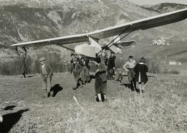 Sul set del film "L'ebbrezza del cielo" - Regia Giorgio Ferroni, 1940 - Un gruppo di attori non identificati trasporta a spalla l'aliante, accompagnati da dei bambini non identificati.