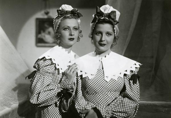 Scena del film "Le educande di Saint-Cyr" - Regia Gennaro Righelli, 1939 - Silvana Jachino, a sinistra, poggia la mano destra sulla spalla di Vanna Vanni, a destra. Entrambe, guardano dritto davanti sé.