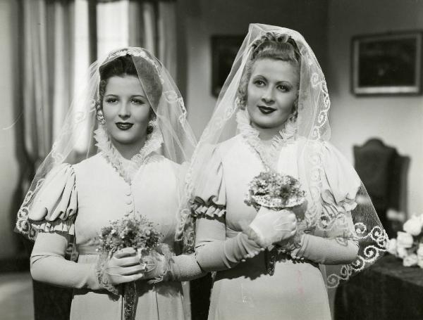 Scena del film "Le educande di Saint-Cyr" - Regia Gennaro Righelli, 1939 - A sinistra, Vanna Vanni e, a destra, Silvana Jachino, in abiti nuziali. Le attrici guardano dritto davanti a loro e reggono tra le mani un bouquet.