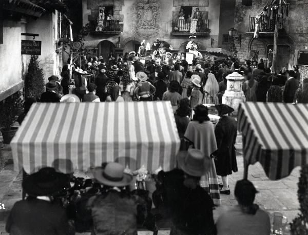 Scena del film "Elisir d'amore" - Regia Amleto Palermi, 1941 - Totale di una piazza in cui è presente un gran numero di attori non identificati che ascoltano Armando Falconi, in piedi su un calesse.