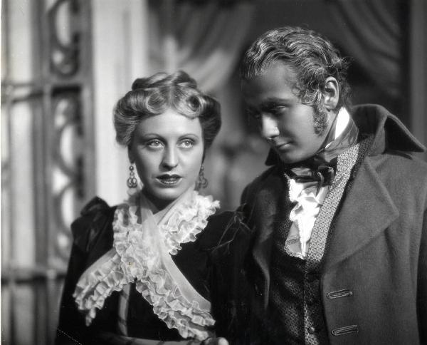 Scena del film "Elisir d'amore" - Regia Amleto Palermi, 1941 - A destra, Roberto Villa osserva con attenzione Margherita Carosio, a sinistra, che guarda dritto davanti a sé.