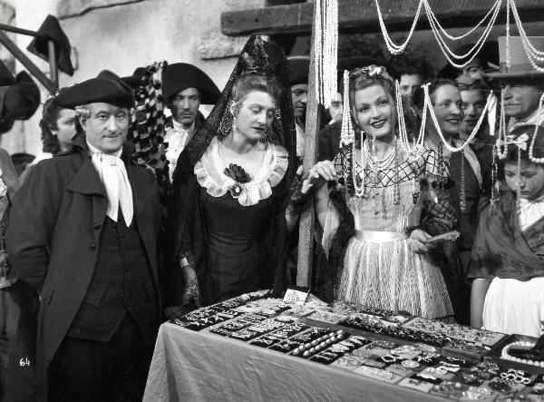 Scena del film "Elisir d'amore" - Regia Amleto Palermi, 1941- A sinistra, Luigi Almirante guarda dritto davanti a sé mentre Margherita Carosio, al centro, osserva l'anello alla mano destra di un'attrice non identificata.