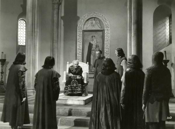 Scena del film "Enrico IV" - Regia Giorgio Pastina, 1943 - Antonio Battistella, a destra, e Lauro Gazzolo osservano Osvaldo Valenti che, seduto su un trono, parla a degli attori non identificati di spalle.