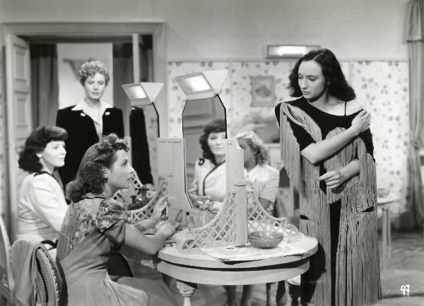Scena del film "Enrico IV" - Regia Giorgio Pastina, 1943 - A destra, Rubi D'Alma si scopre la spalla sinistra mentre delle attrici non identificate la osservano.