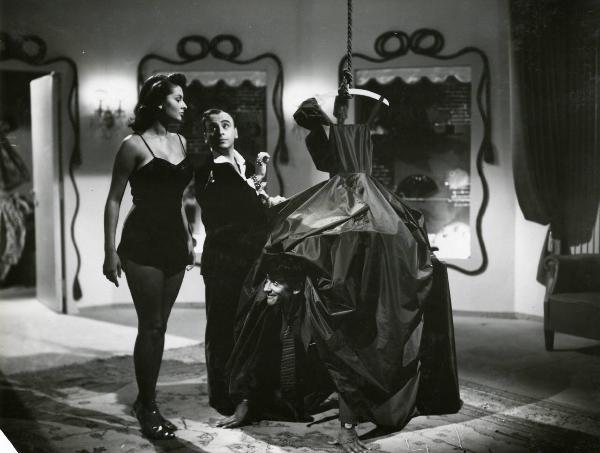 Scena del film "Era lui si si" - Regia Vittorio Metz, Marcello Marchesi, Marino Girolami, 1951 - Walter Chiari compare inginocchiato da sotto la gonna di un abito ampio mentre Sofia Loren e Bruno Corelli si guardano.