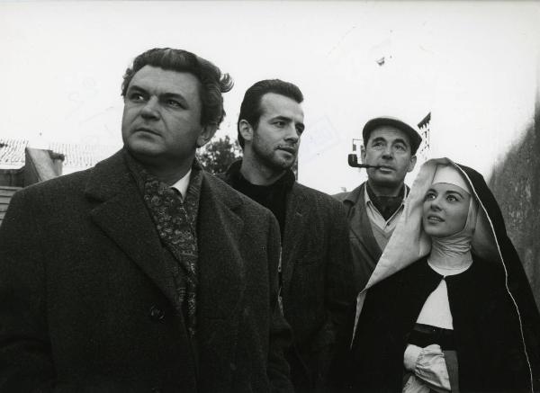 Scena del film "Era notte a Roma" - Regia Roberto Rossellini, 1960 - Serghej Bondarciuk, a sinistra, Leon Genn e un'attrice non identificata, in abiti religiosi, rivolgono lo sguardo in alto a sinistra mentre Peter Baldwin osserva a destra.