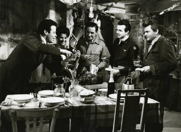 Scena del film "Era notte a Roma" - Regia Roberto Rossellini, 1960 - Renato Salvatori, a sinistra, serve del vino mentre, Giovanna Ralli, alla sua destra, Leon Genn, al centro, Peter Baldwin e Serghej Bondarciuk, a destra, lo osservano.