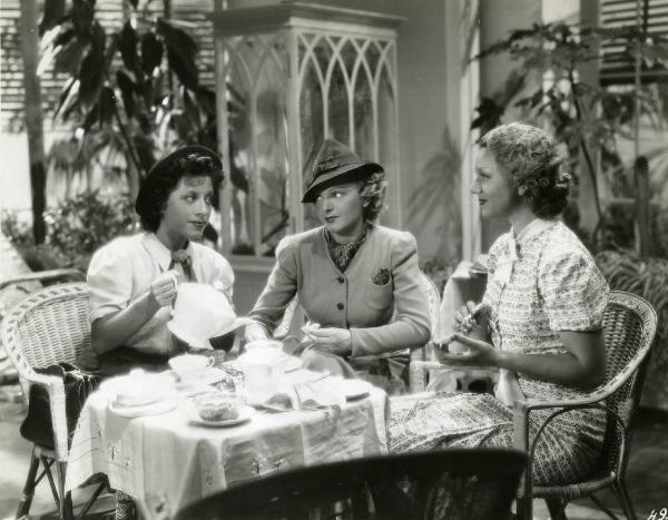 Scena del film "Eravamo 7 sorelle" - Regia Nunzio Malasomma, 1939 - Sedute a un tavolo, Lotte Menas, al centro, e Ninì Gordini Cervi, a destra, osservano sorridenti Paola Barbara mentre versa del tè.
