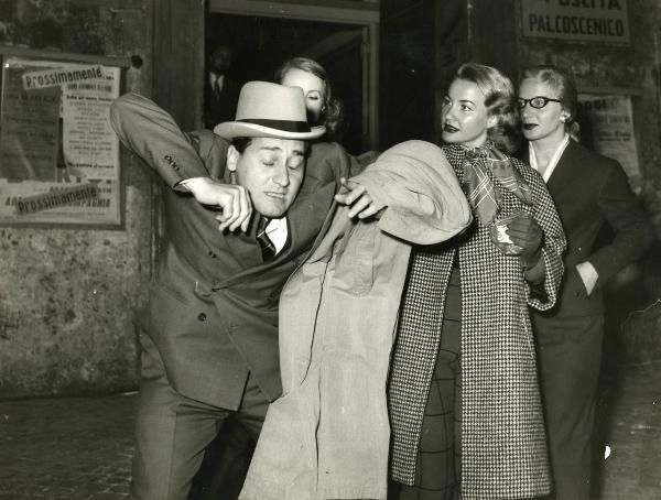 Scena del film "Un eroe dei nostri tempi" - Regia Mario Monicelli, 1955 - Alberto Sordi, in primo piano, a occhi chiusi e con le braccia alzate, si sporge in avanti. Alle sue spalle tre attrici non identificate.