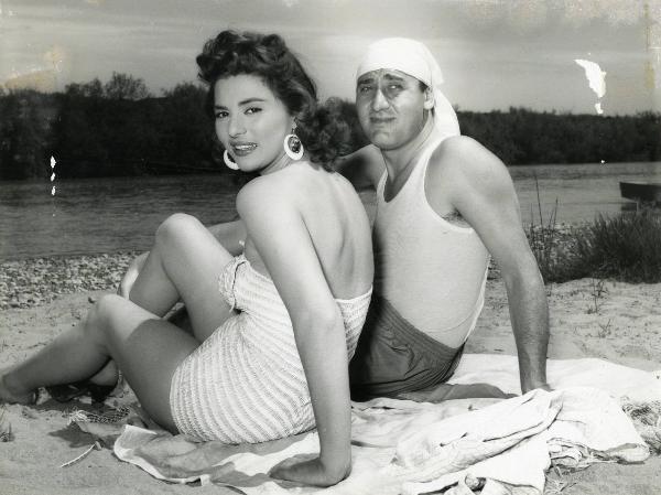 Scena del film "Un eroe dei nostri tempi" - Regia Mario Monicelli, 1955 - Seduti su una spiaggia: Giovanna Ralli appoggia la mano destra alla gamba destra e guarda verso l'obbiettivo, mentre Alberto Sordi rivolge lo sguardo verso destra.