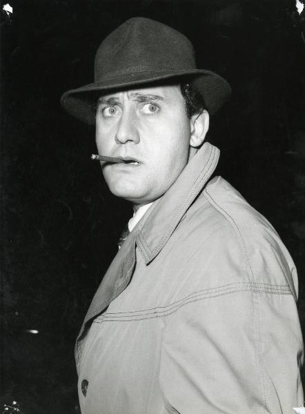 Scena del film "Un eroe dei nostri tempi" - Regia Mario Monicelli, 1955 - Mezza figura di Alberto Sordi che, con una sigaretta in bocca, rivolge lo sguardo verso destra.