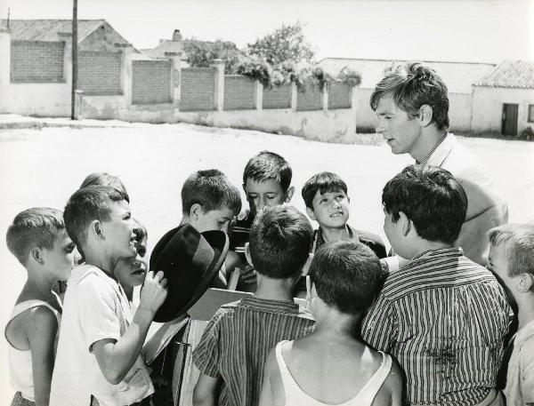 Scena del film "Eroe vagabondo" - Regia Walter Santesso, 1966 - Walter Santesso, al centro, è attorniato da alcuni piccoli attori non identificati che lo ascoltano. Il piccolo attore di fronte a lui regge in mano un cappello.