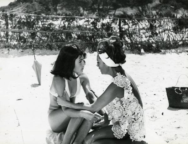Scena del film "L'estate" - Regia Paolo Spinola, 1966 - Sedute su una spiaggia, un'attrice non identificata a destra, afferra Mita Medici per le braccia, a sinistra.