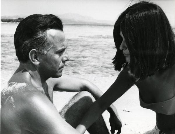Scena del film "L'estate" - Regia Paolo Spinola, 1966 - Enrico Maria Salerno e Mita Medici, entrambi di profilo, si osservano seduti su una spiaggia davanti al mare.