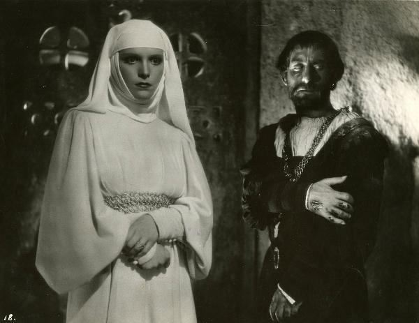 Scena del film "Ettore fieramosca" - Regia Alessandro Blasetti, 1938 - Umberto Sacripante volge lo sguardo a destra e si porta la mano destra al braccio mentre Elisa Cegani, a sinistra, stringendosi il polso destro volge lo sguardo davanti a sé.