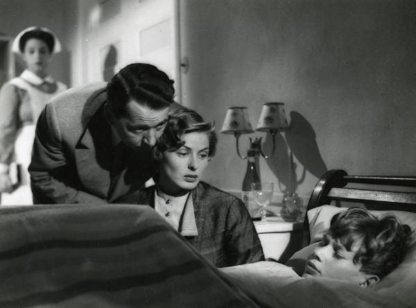 Scena del film "Europa 51" - Regia Roberto Rossellini, 1952 - Ingrid Bergman osserva Sandro Franchina, disteso a letto, mentre Alexander Knox, le si avvicina all'orecchio. In secondo piano un'attrice non identificata in vesti da infermiera.