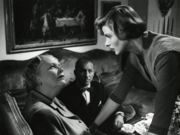 Scena del film "Europa 51" - Regia Roberto Rossellini, 1952 - A destra, Ingrid Bergman, protesa in avanti, guarda un'attrice non identificata, a sinistra, che la guarda. In secondo piano un attore non identificato seduto osserva la scena.