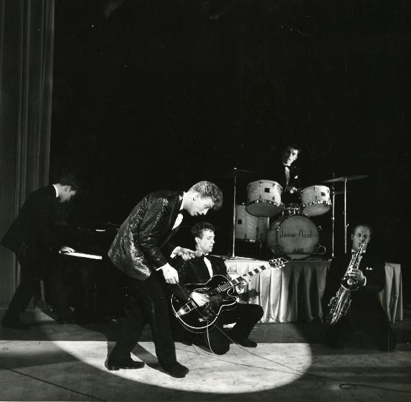 Scena del film "Europa di notte" - Regia Alessandro Blasetti, 1959 - Una band di attori non identificati suonano rispettivamente il piano, la batteria, la tromba e la chitarra. In primo piano, l'ultimo attore non identificato ha in mano un microfono.