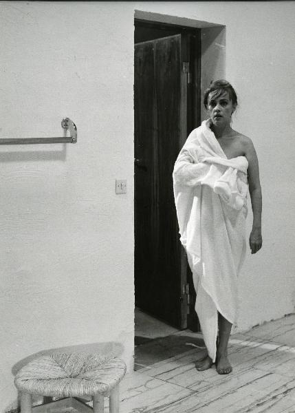 Scena del film "Eva" - Regia Joseph Losey, 1962 - Davanti a una porta aperta, Jeanna Moreau, in piedi coperta da un asciugamano, osserva dritto davanto a sé.