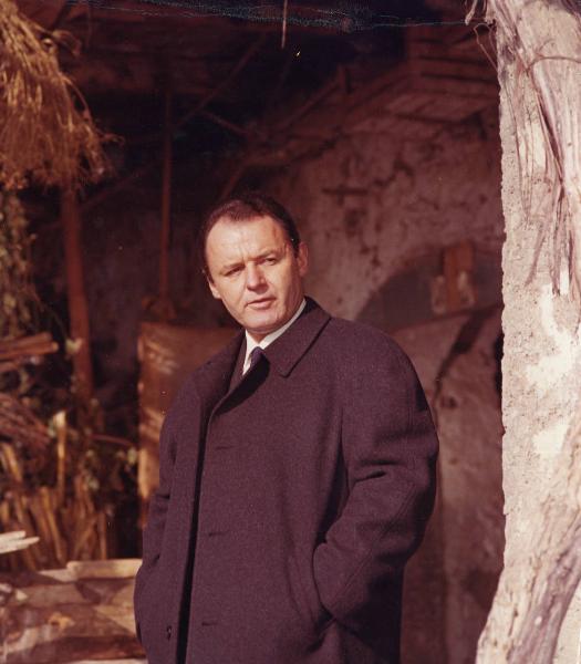 Scena del film "E venne un uomo" - Regia Ermanno Olmi, 1965 - Mezza figura di Rod Steiger che, con le mani nelle tasche del cappotto, rivolge lo sguardo verso destra.