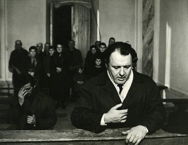 Scena del film "E venne un uomo" - Regia Ermanno Olmi, 1965 - In primo piano a destra, Rod Steiger é inginocchiato su una panca di una chiesa. In secondo piano, attori non identificati.