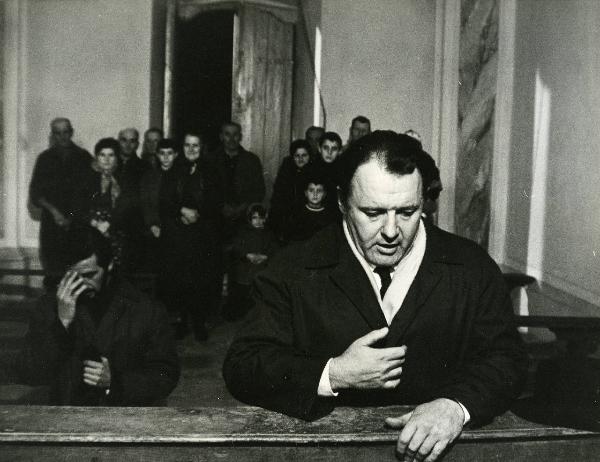 Scena del film "E venne un uomo" - Regia Ermanno Olmi, 1965 - In primo piano a destra, Rod Steiger é inginocchiato su una panca di una chiesa. In secondo piano, attori non identificati.