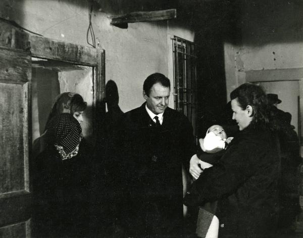 Scena del film "E venne un uomo" - Regia Ermanno Olmi, 1965 - Al centro, Rod Steiger guarda verso il bambino appena nato a destra, tenuto in braccio da un attrice non identificata. A sinistra, altre due attrici non identificate.