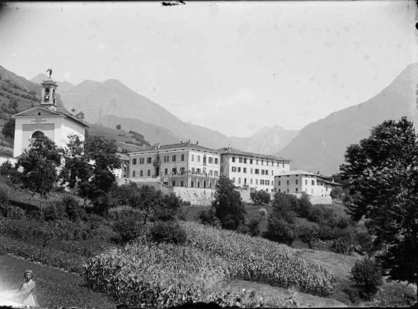 Valnegra. Veduta panoramica con la chiesa parrocchiale di San Michele, il Collegio San Carlo e, in primo piano, un campo di granoturco