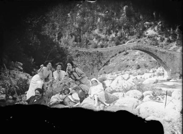 Val Brembana. Ritratto di una famiglia in gita presso un torrente con ponte sullo sfondo