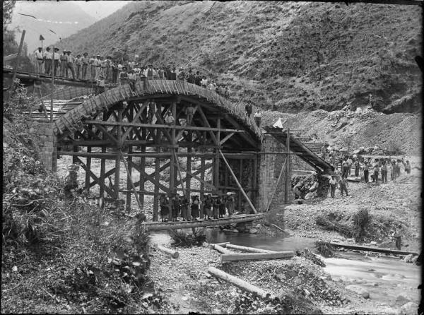 Val Brembana. Costruzione di un ponte sul Brembo per il passaggio della ferrovia. Operai e contadine con gerle sulle spalle