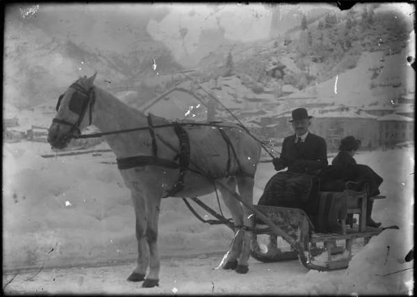 Piazza Brembana. Domenico Mocchi, medico condotto, si reca dai pazienti in slitta trainata da cavallo. Veduta del paese innevato sullo sfondo