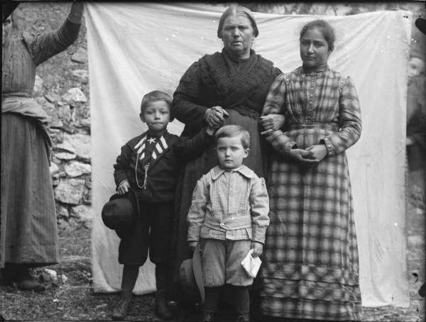 Val Brembana. Ritratto di un gruppo familiare con casa rurale sullo sfondo